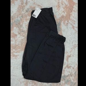 Dark grey in color, has two side pockets, slim straight fit, unworn with tags